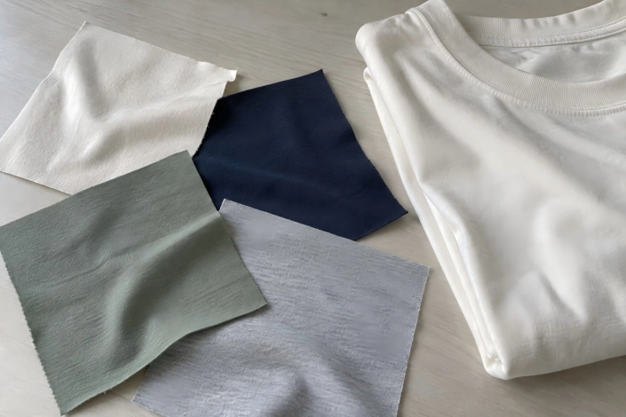 Fabric swatches beside a folded T-shirt on a sample table